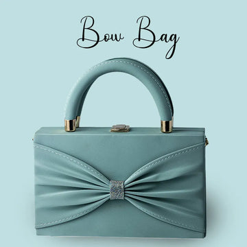 Teal handbag with a bow detail on a light blue background