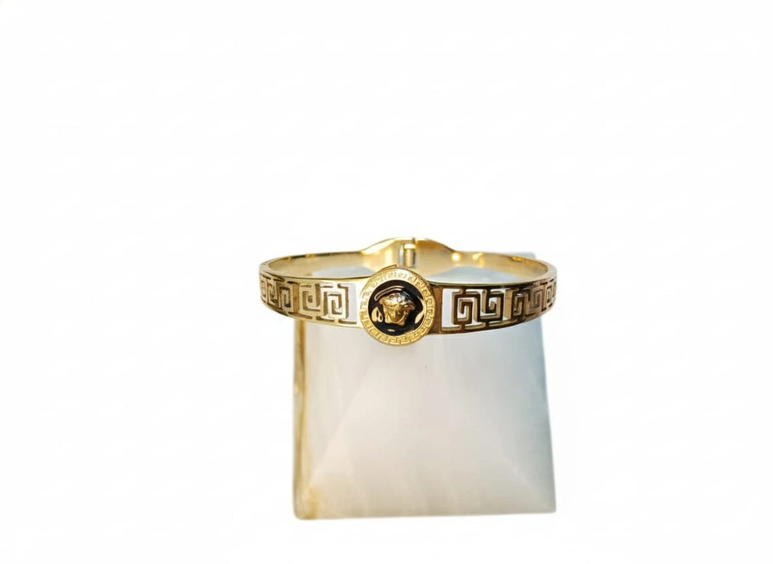 Gold bracelet with a central emblem on a white background