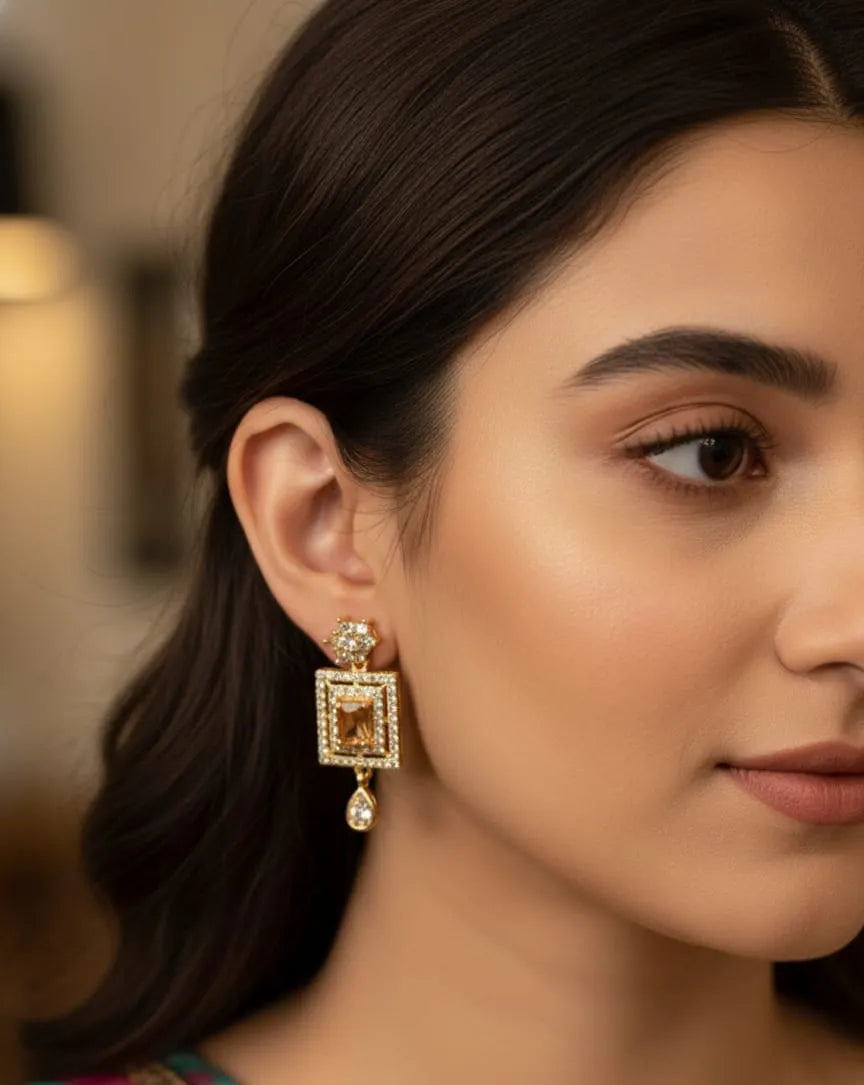 Woman wearing gold earrings with a blurred background