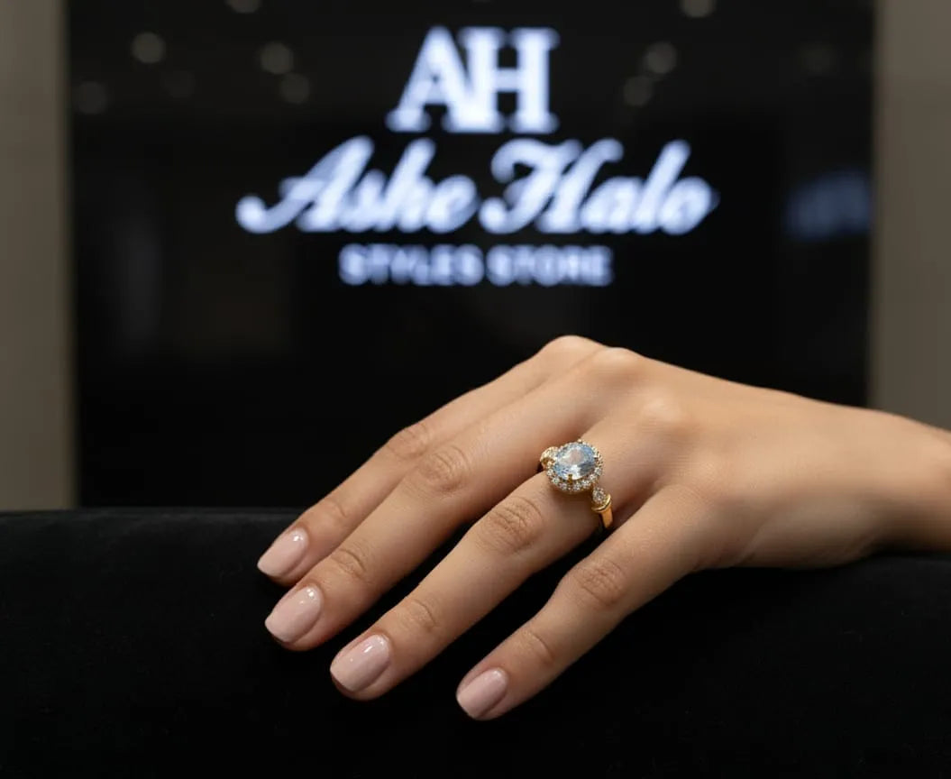 Hand wearing a gold ring with a clear stone against a dark background with 'Ashe Halo' branding.