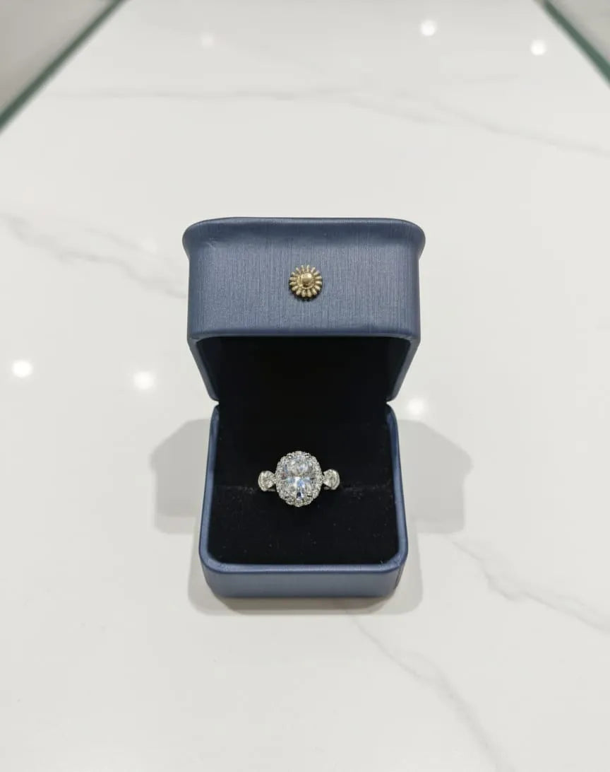 Hand wearing a gold ring with a clear stone against a dark background with 'Ashe Halo' branding.