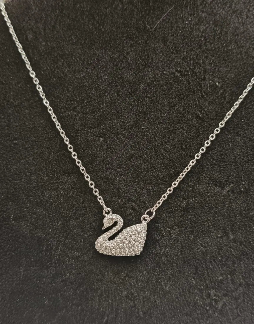 Silver swan pendant necklace on a dark textured background