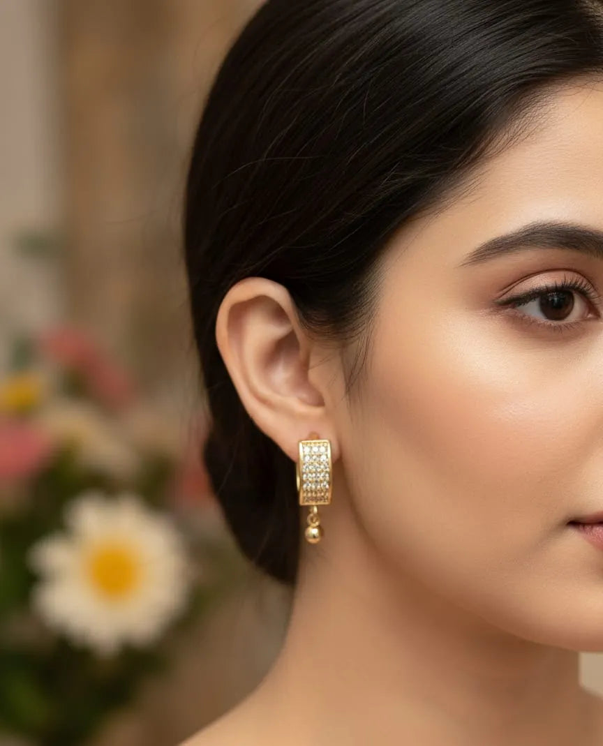 Close-up of a woman wearing gold earrings with a blurred floral background