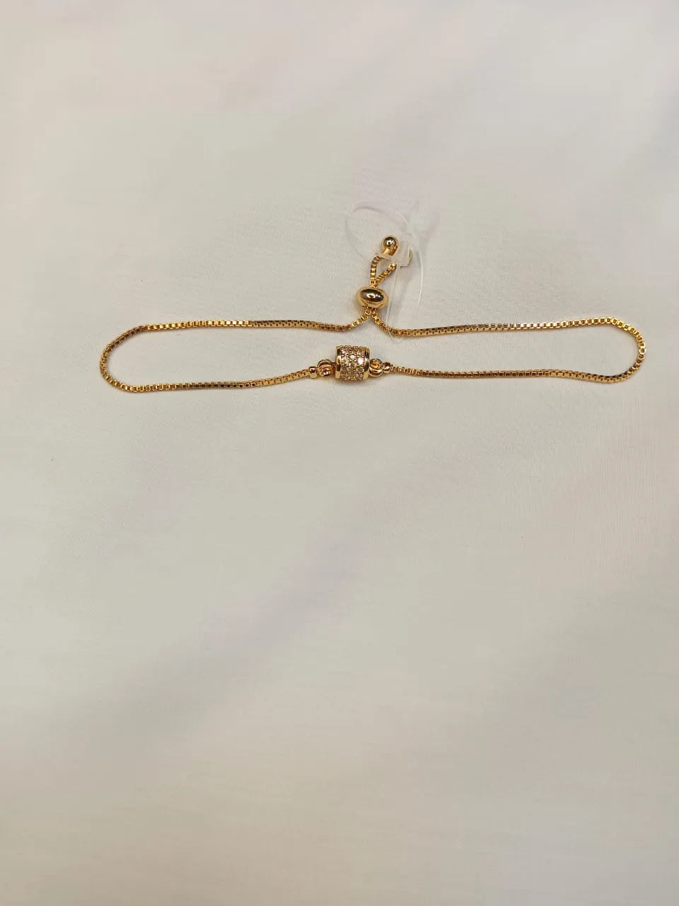 Gold bracelet on a wrist with flowers in the background