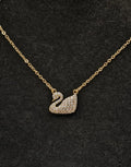 Gold necklace with a swan pendant on a black background