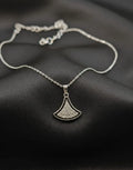 Silver necklace with a pendant on a dark fabric background