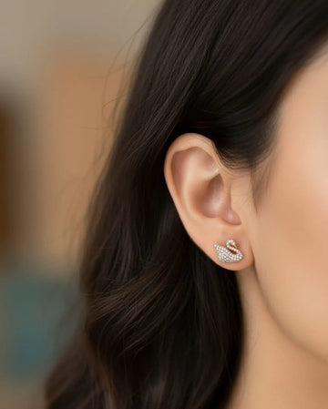 Close-up of an ear wearing a diamond earring with a blurred background