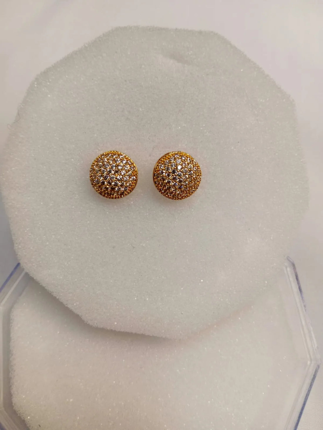 Gold earrings with gemstones on a white stand