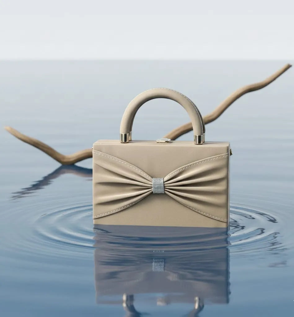 Beige handbag with a bow detail on a reflective water surface