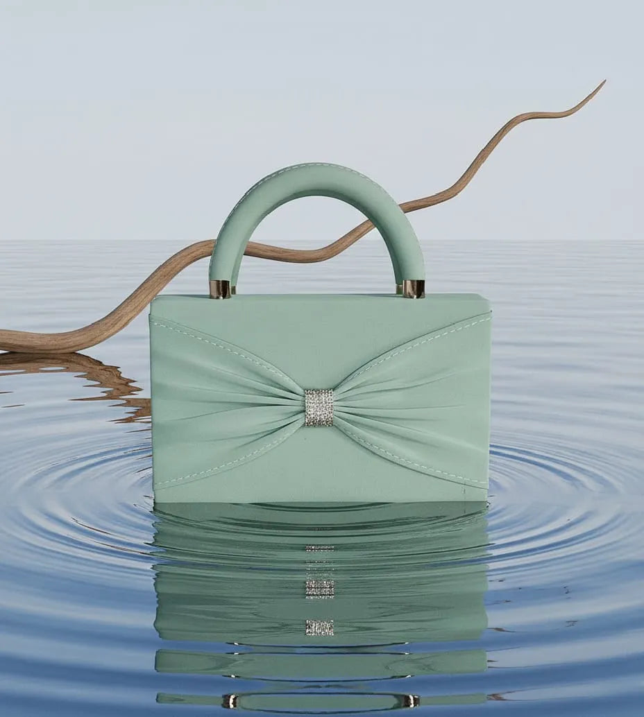Mint green handbag with a bow and crystal detail on a water surface