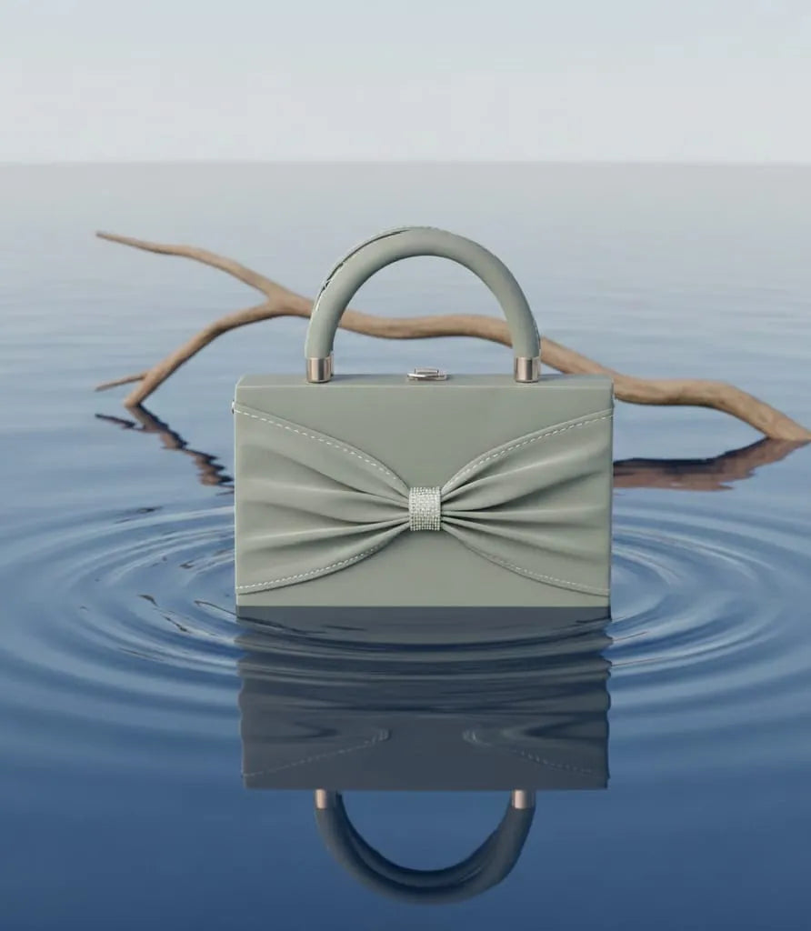 Green handbag with a bow design on a water surface