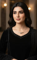 Woman wearing a black top and necklace with a blurred background