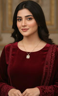Woman wearing a red traditional outfit with intricate designs and a necklace.
