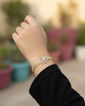 Hand wearing a decorative bracelet with a blurred outdoor background