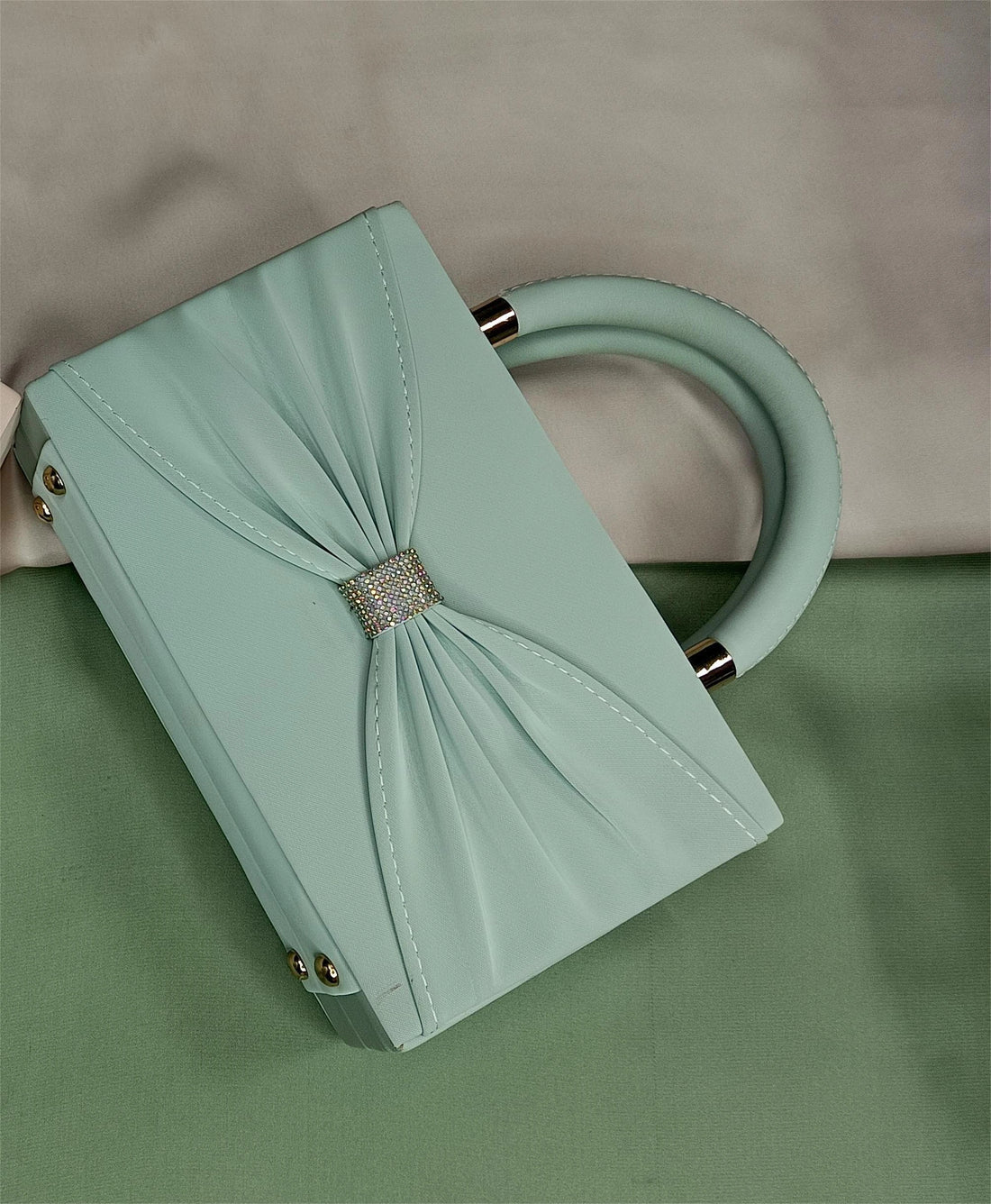 Mint green handbag with a bow and crystal detail on a water surface
