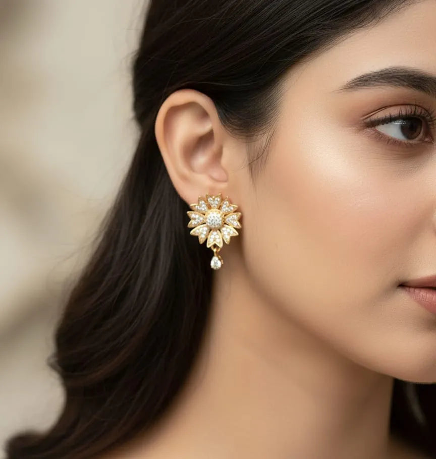 Close-up of a woman wearing a gold earring with a central gemstone and pearl.