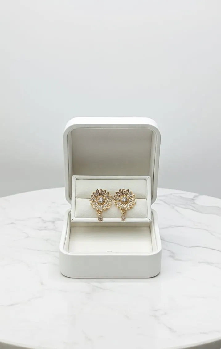 Close-up of a woman wearing a gold earring with a central gemstone and pearl.